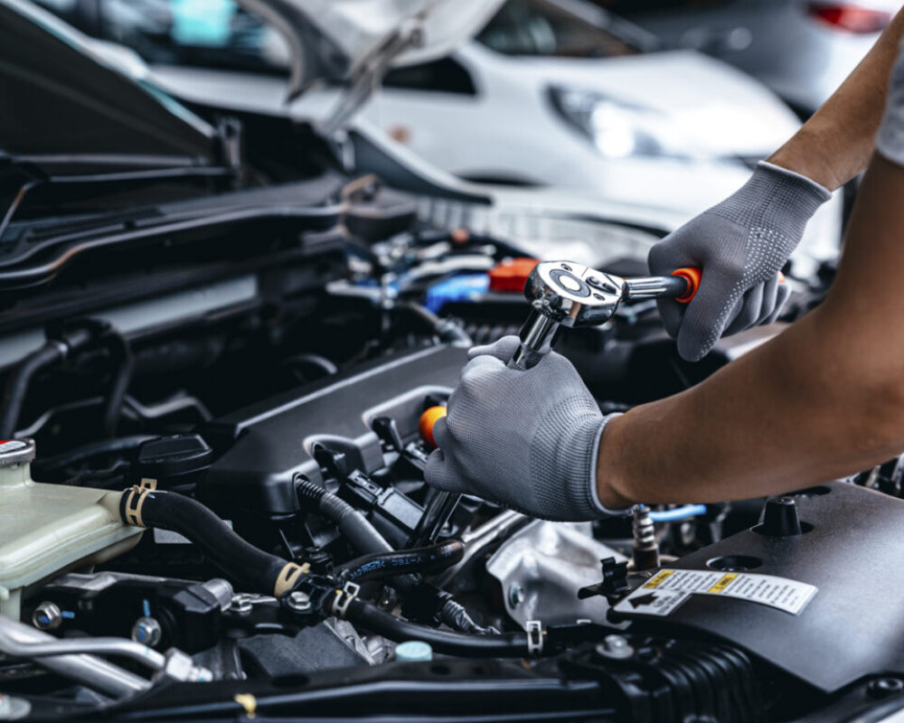 Mechanic using wrench while working on car engine at garage work